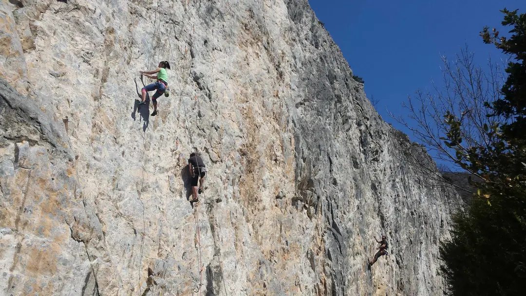 Two climbers on a tall grey limestone wall