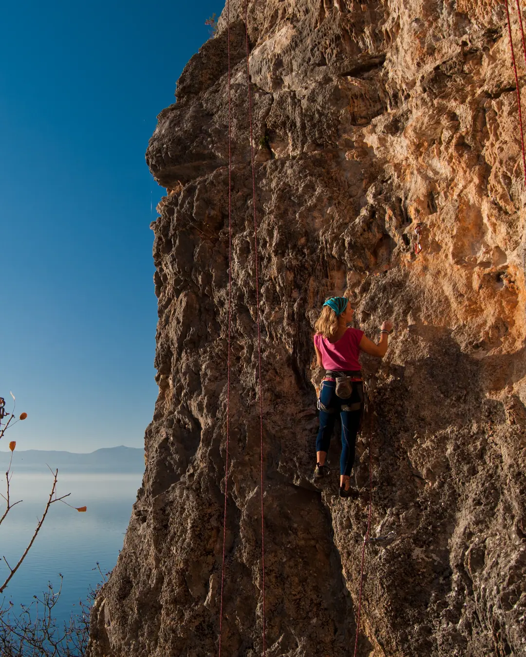 Climber on an orange limestone wall above Lake Ohrid