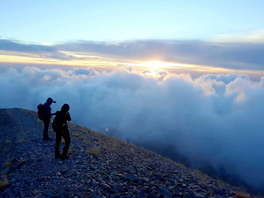Hikers above a sea of clouds at sunrise