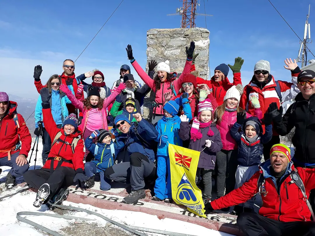 Big group of hikers cheering on a snowy summit